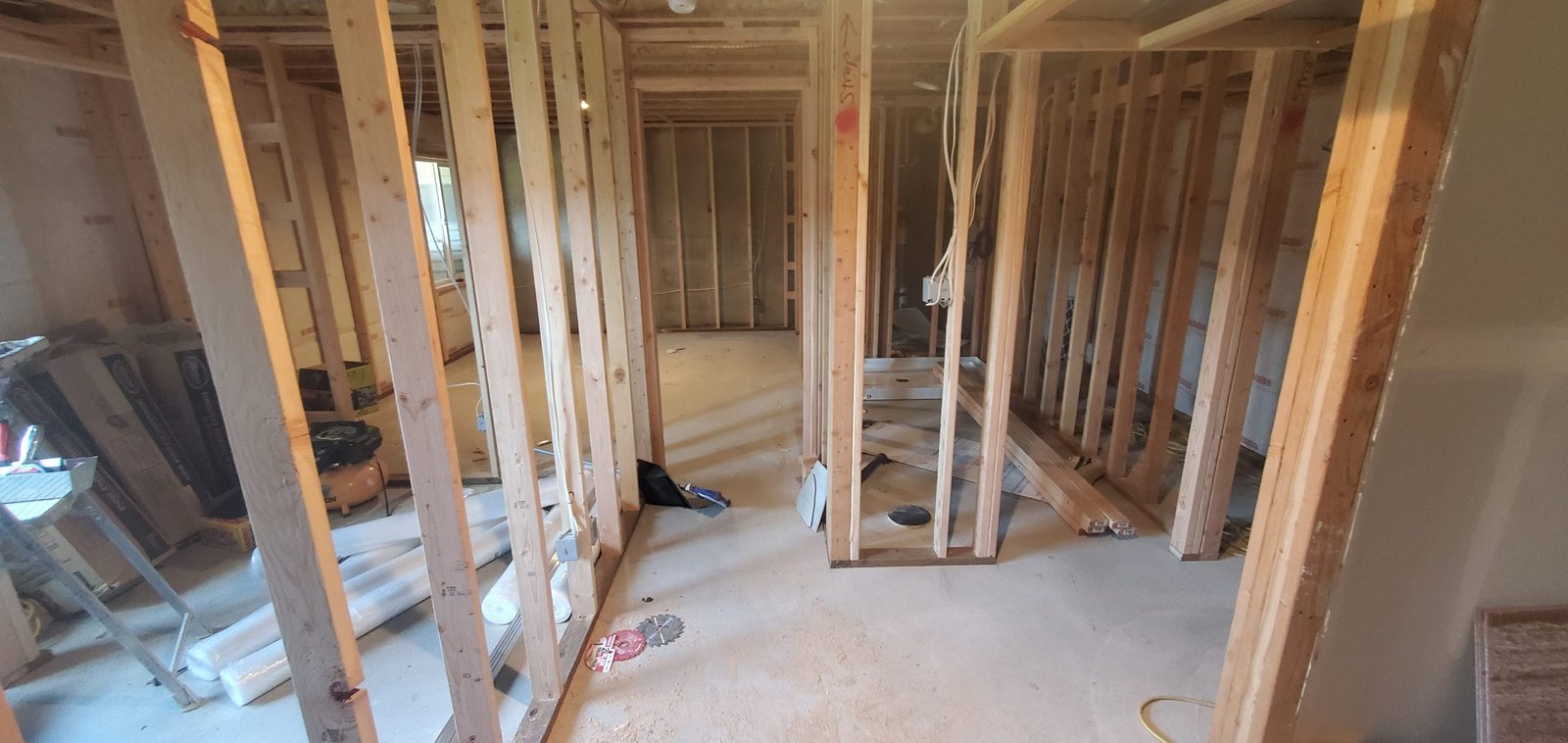 Basement renovation in progress with wood stud walls, insulation, electrical wiring, and outlets.