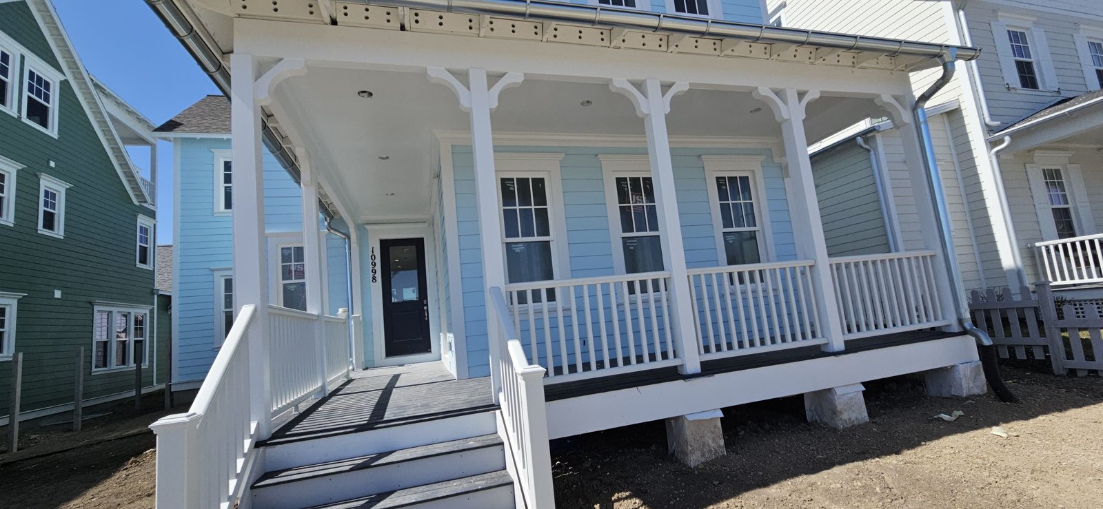 Light blue house in Utah with a white porch and decorative trim, featuring a welcoming front entrance.