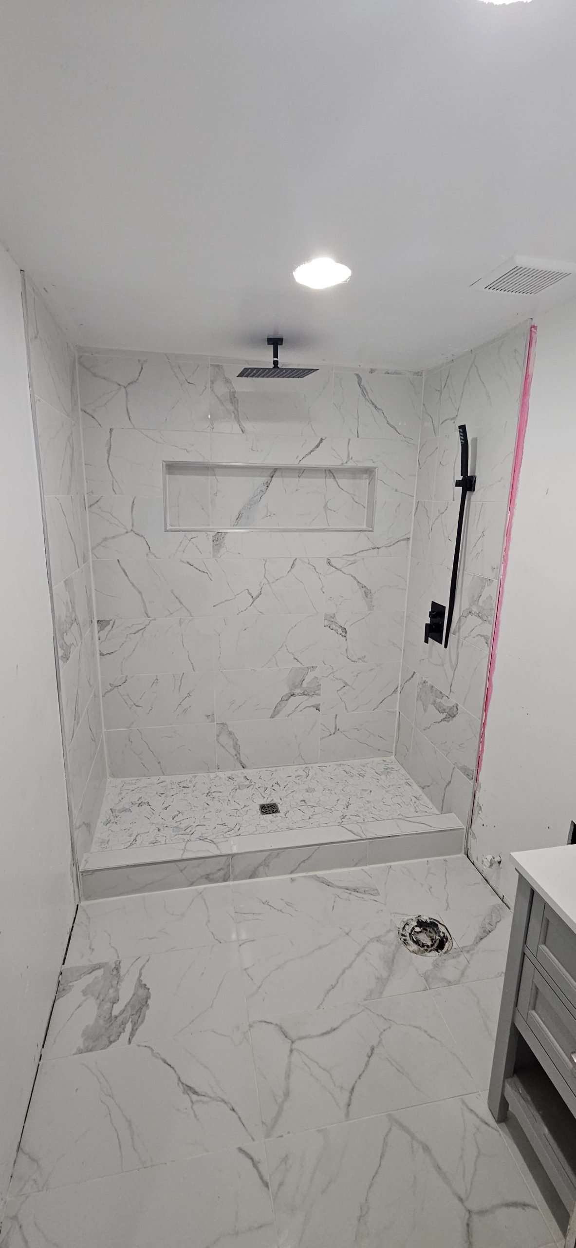 Luxurious bathroom featuring a large walk-in shower with white marble tiles, rainfall showerhead, and glass door.