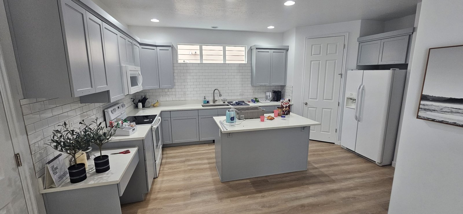 Kitchen renovation in Utah featuring freshly painted gray cabinets, white subway tile backsplash, and stainless steel appliances.