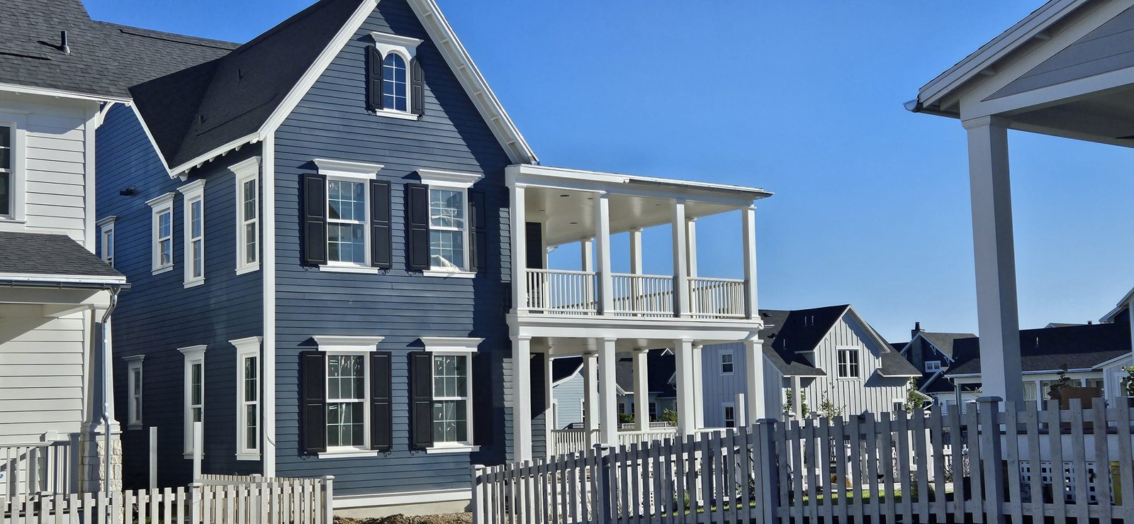 Utah home with newly painted blue exterior, featuring white porch and black shutters.