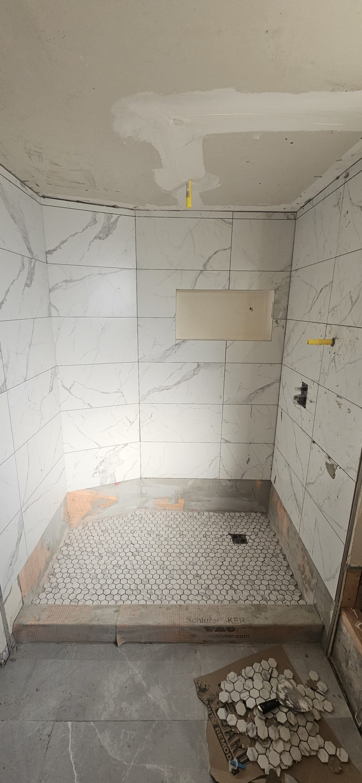 Bathroom renovation in Utah featuring white marble tile installation on walls and shower floor.