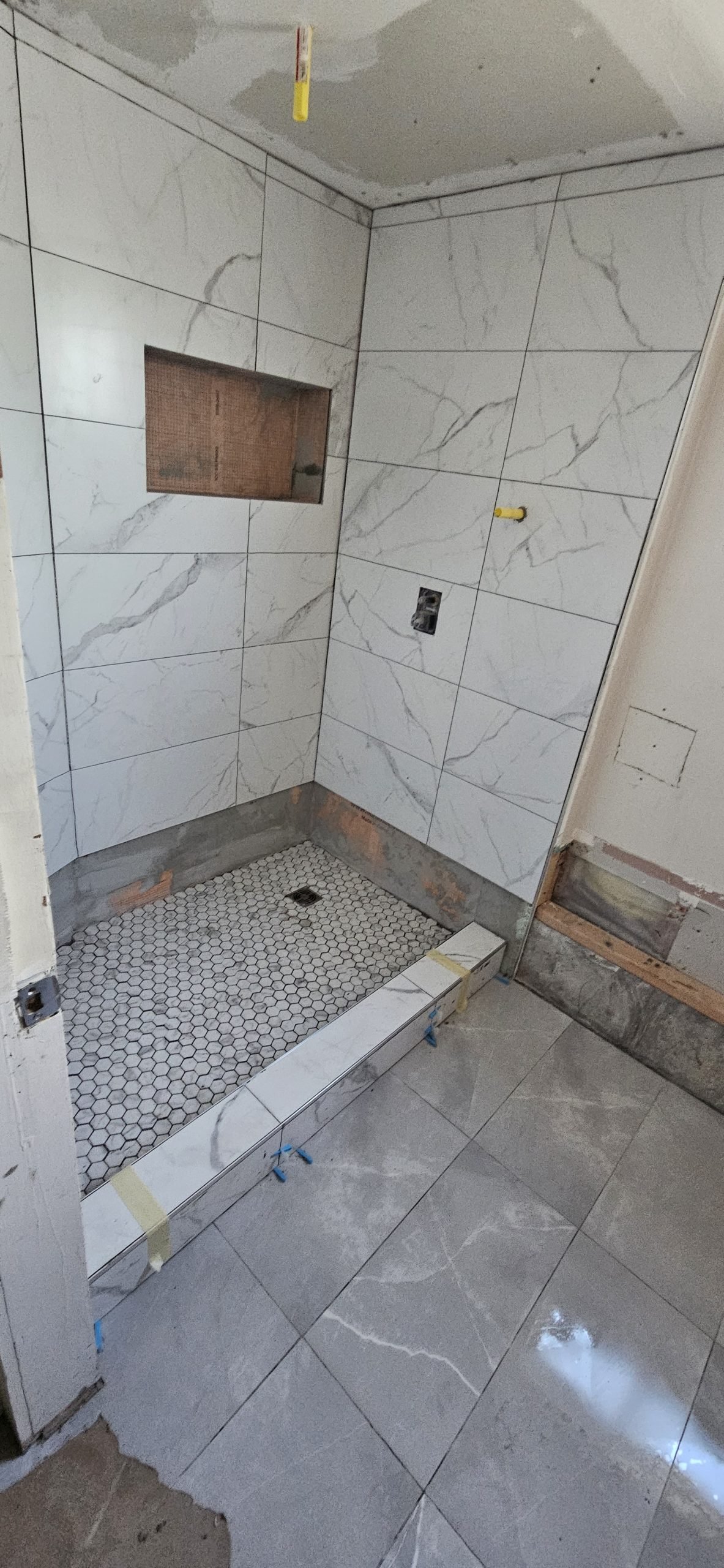 Modern bathroom renovation in Utah featuring white marble wall tiles and gray mosaic shower floor.