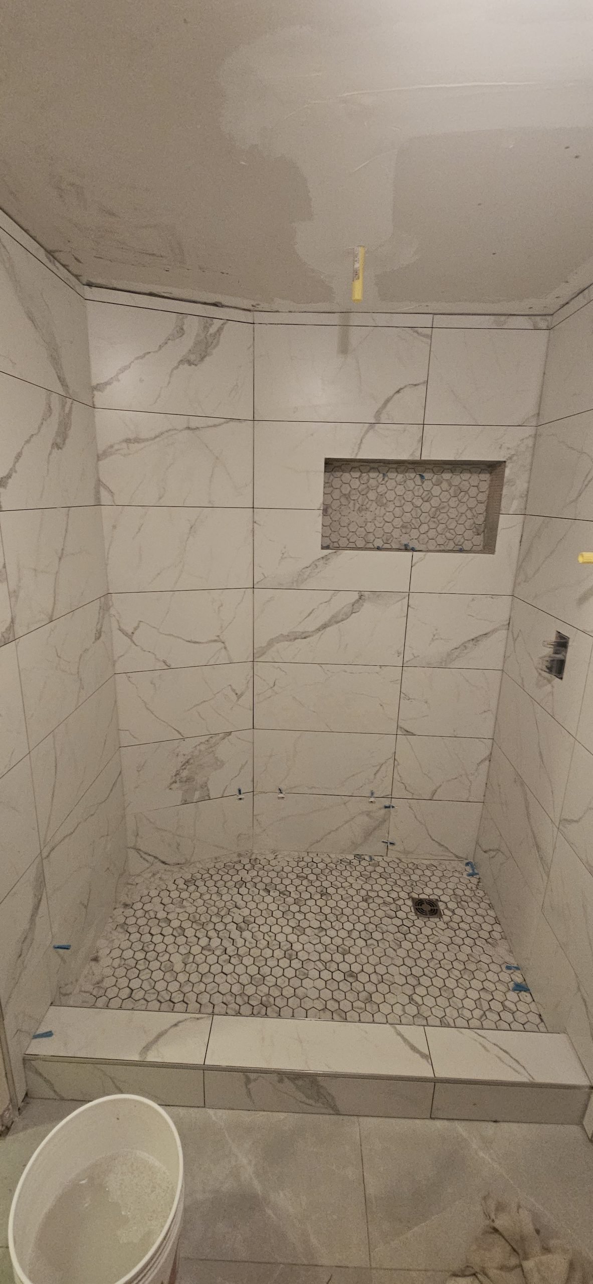 Bathroom renovation in Utah featuring white marble wall tiles and mosaic shower floor.