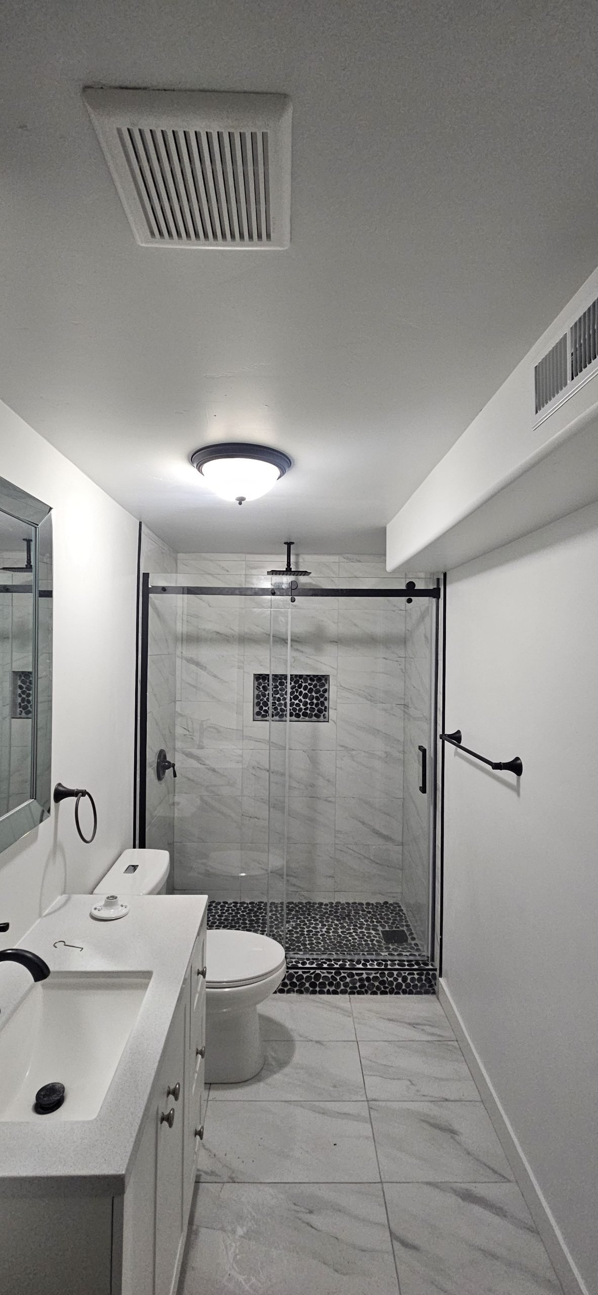 Luxurious bathroom featuring a walk-in shower with marble tiles and pebble mosaic floor.