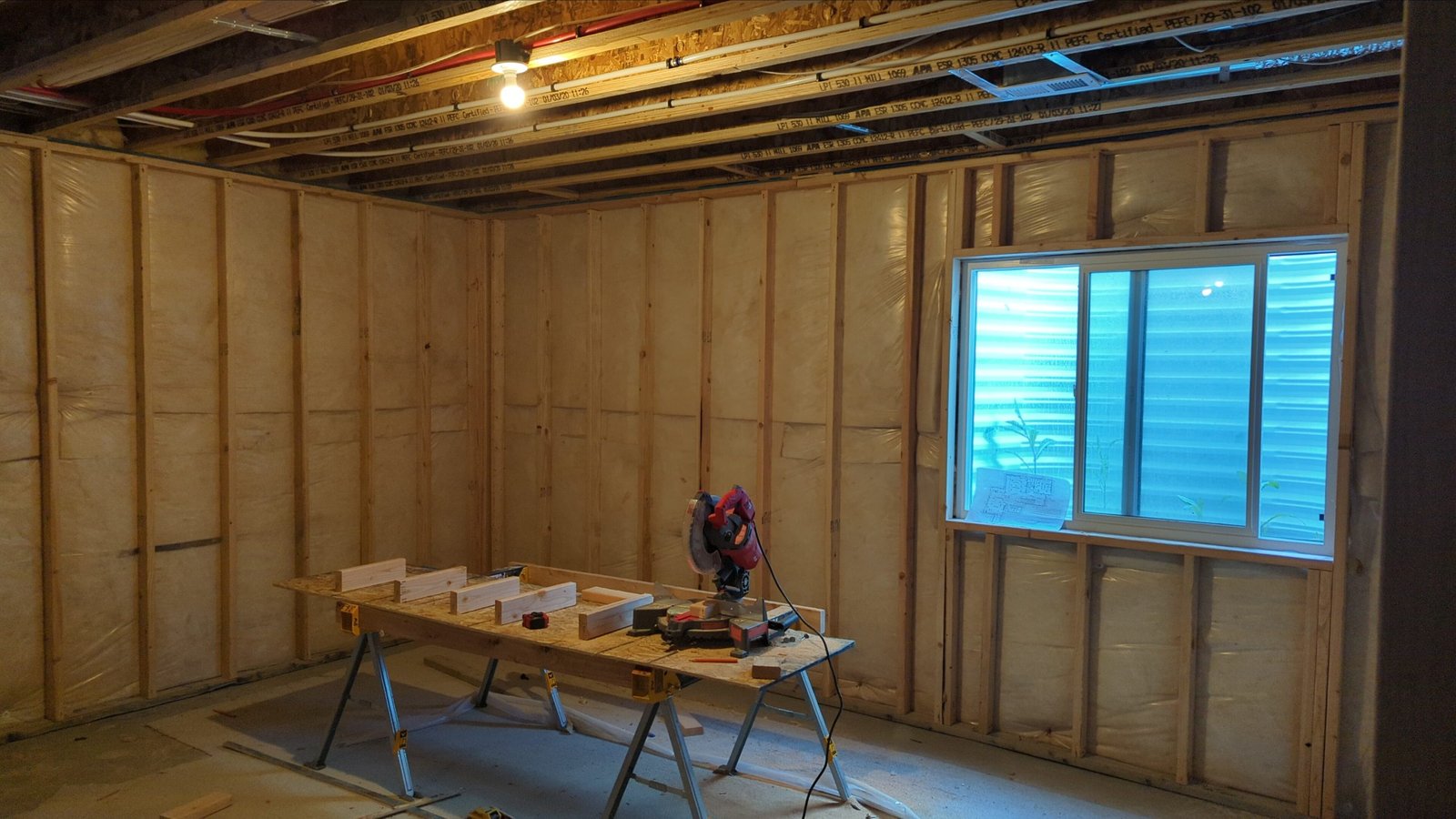 Basement remodeling project showing framed walls, insulation, and a work-in-progress area.