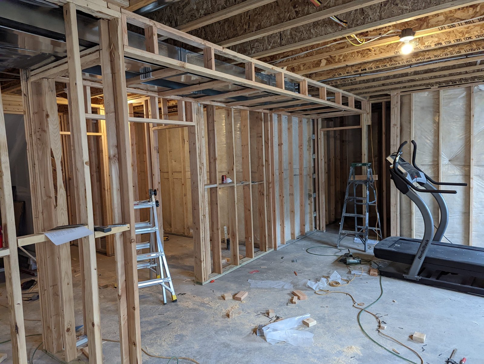 Basement renovation project with framed walls, insulation, and electrical work in progress.