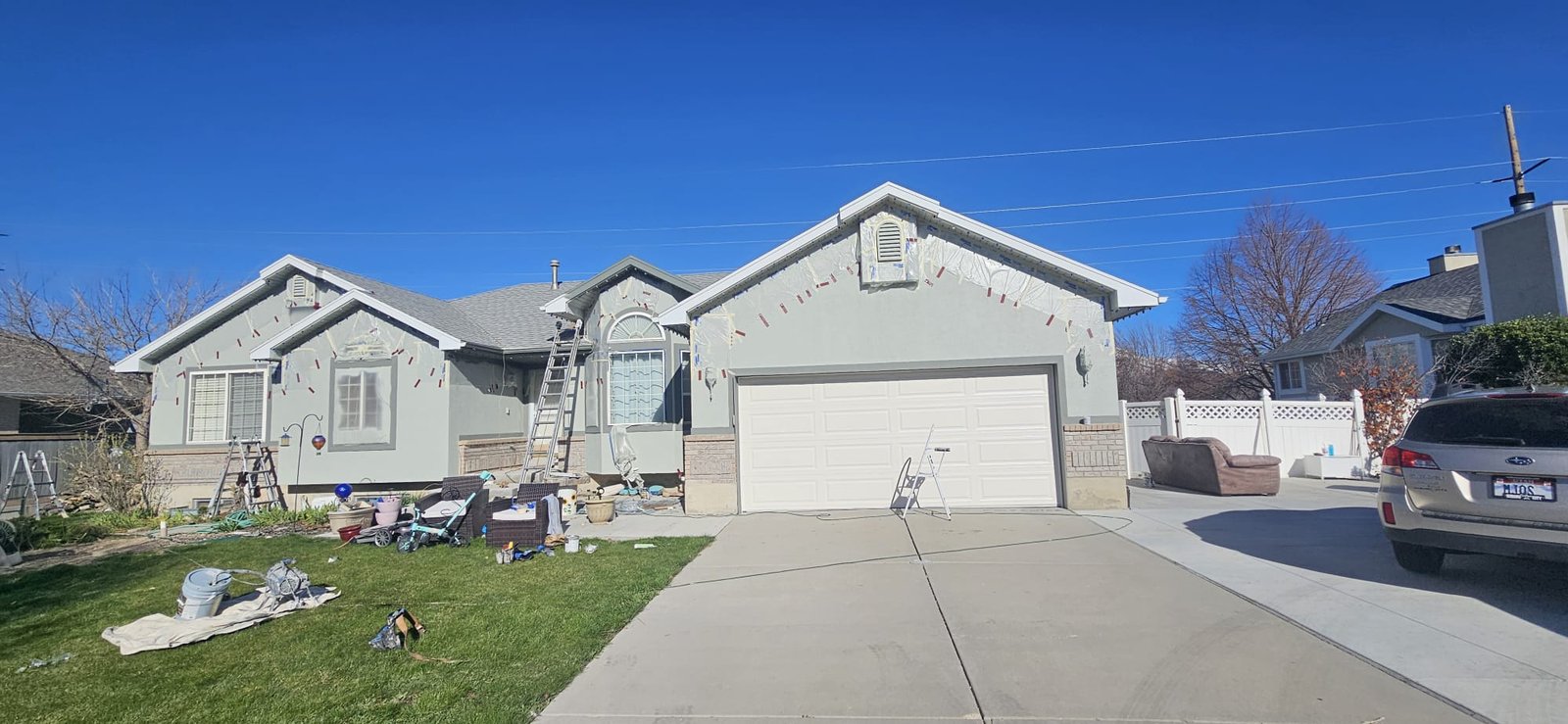 Exterior home painting project in Utah, featuring gray stucco and white trim.