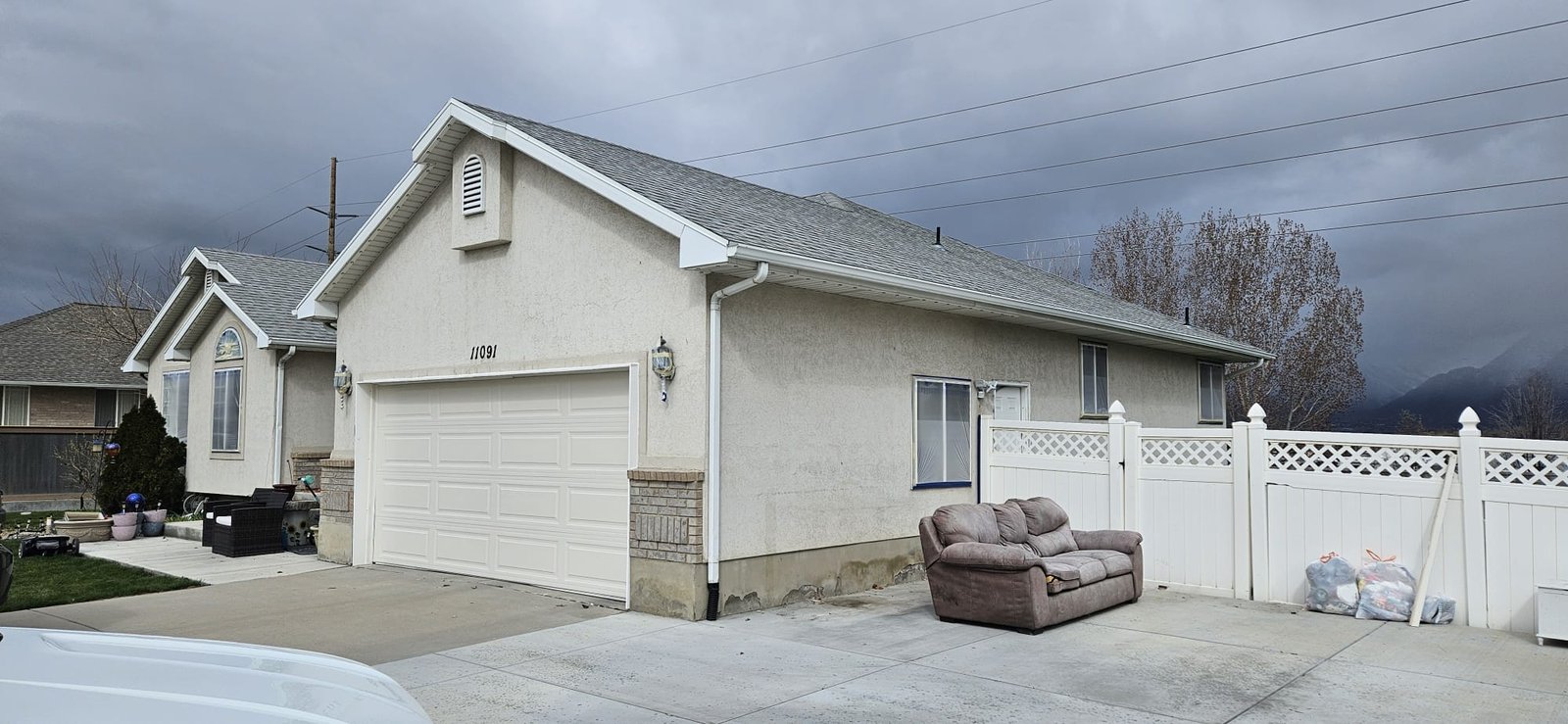 Utah home before painting with beige exterior, two-car garage, and front porch.