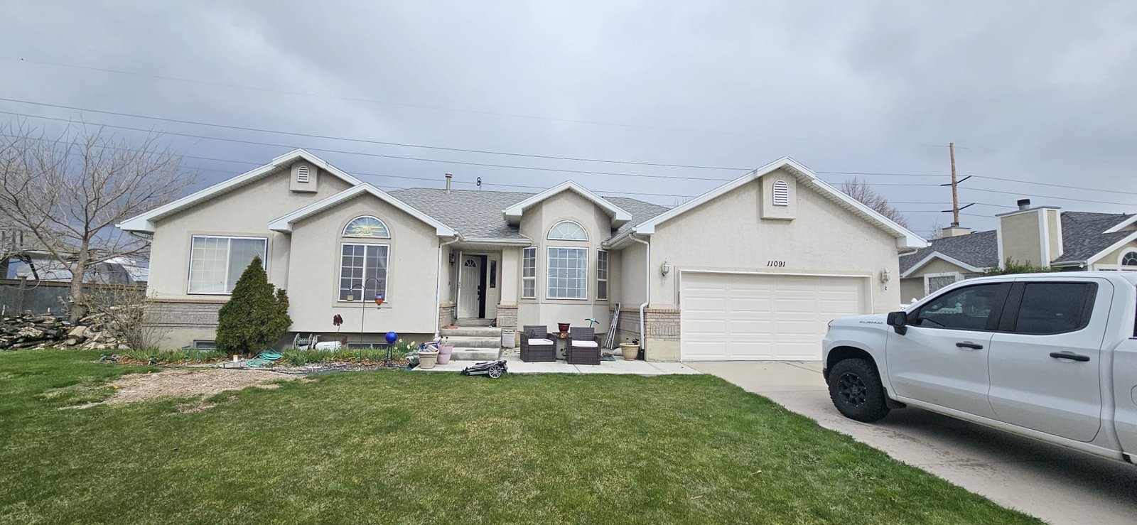 preparing to paint Utah home with beige exterior, two-car garage, and front porch.