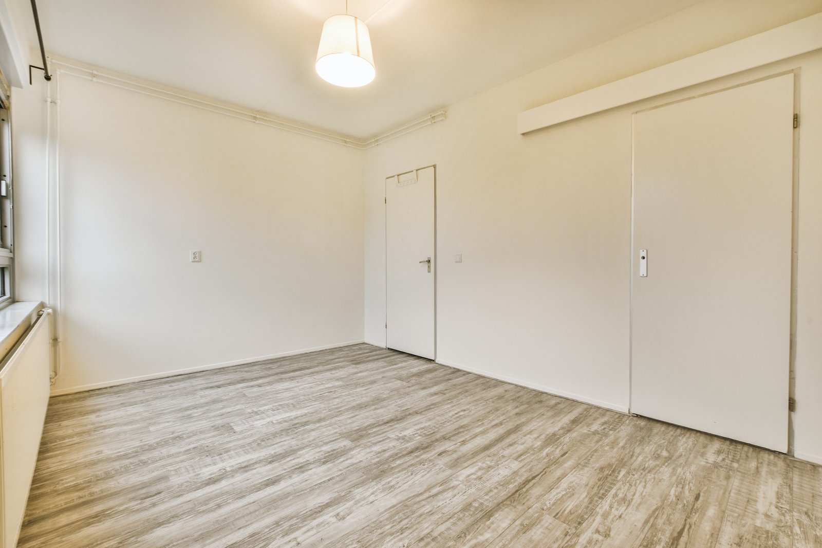 A spacious bright empty room with laminate floors