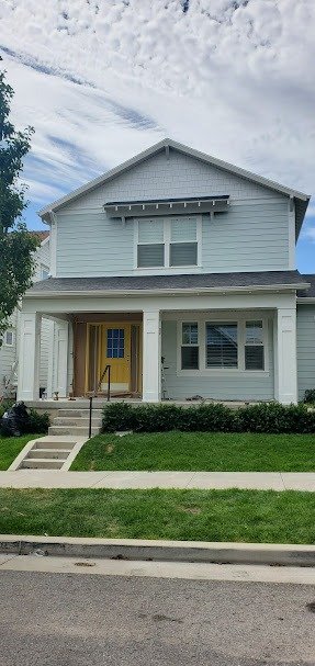 Utah home recently painted, featuring light gray siding, yellow front door, and modern architecture.